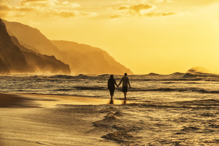 couple walking on beach during sunset in kauai